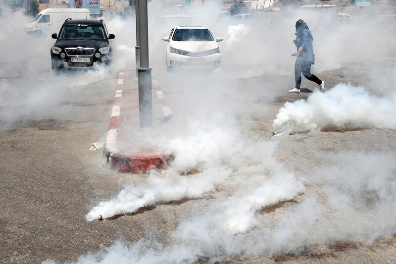 A Palestinian photographer runs away from tear gas fired by Israeli forces during a protest against Bahrain's workshop for the US peace plan, near the Jewish settlement of Beit El, in the Israeli-occupied West Bank.  Reuters