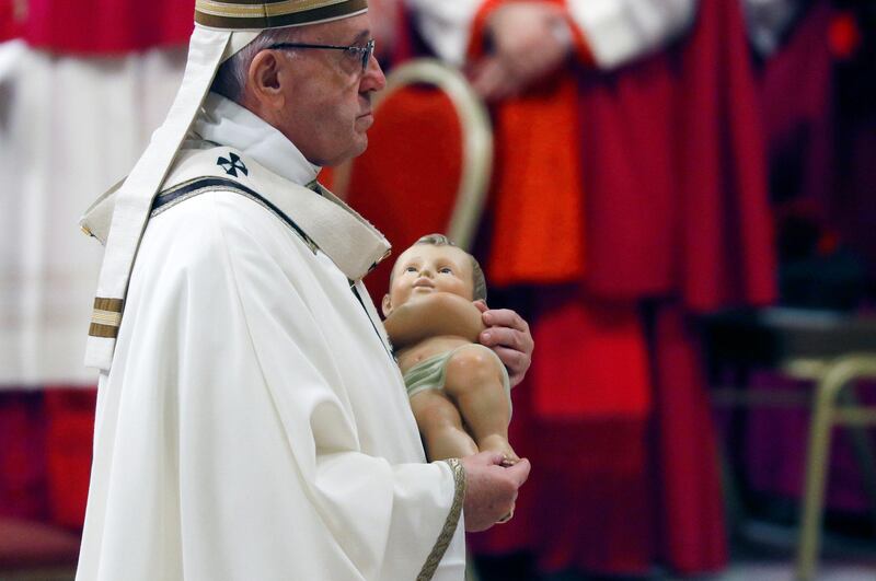 Pope Francis carries a statue of Baby Jesus during the Christmas Eve mass in St Peter's Basilica at the Vatican. Reuters