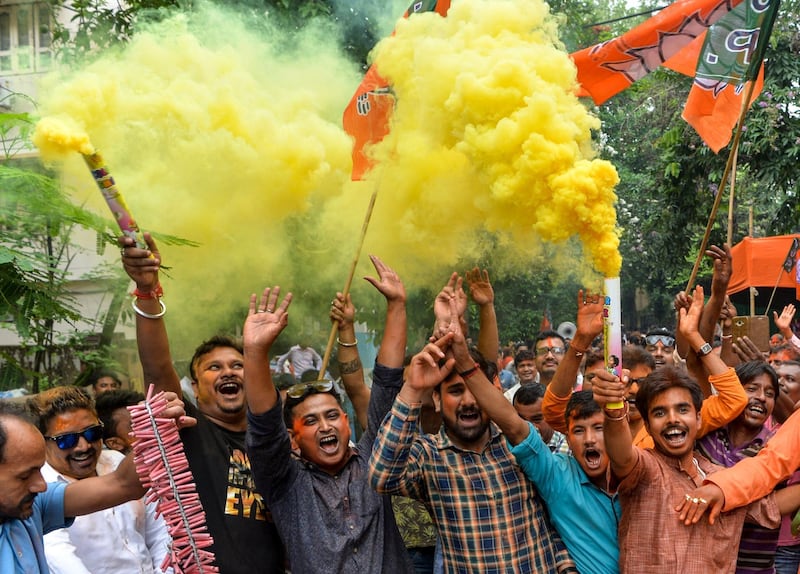 Indian supporters of Bharatiya Janata Party (BJP) hold colour smoke crackers as they celebrate the vote results.  AFP