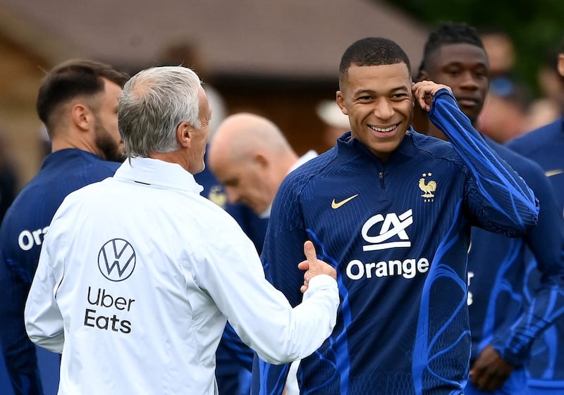France forward Kylian Mbappe smiles next to head coach Didier Deschamps. AFP