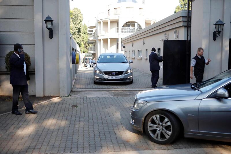 Private security personnel man the gate to the compound of the controversial business family Gupta in Johannesburg while cars belonging to the the Hawks, The Directorate for Priority Crime Investigation, are stationed outside, in Johannesburg, South Africa, on February 14, 2018. 
South African President Zuma's battle to stay in office despite the ruling ANC party reportedly asking him to step down is the latest in a long history of career controversies. Zuma has been involved in several scandals, one known as Guptagate. It involved the president's allegedly corrupt relationship with a wealthy family of Indian immigrants headed by three brothers -- Ajay, Atul and Rajesh Gupta -- who built a business empire in mining, media, technology and engineering. / AFP PHOTO / WIKUS DE WET