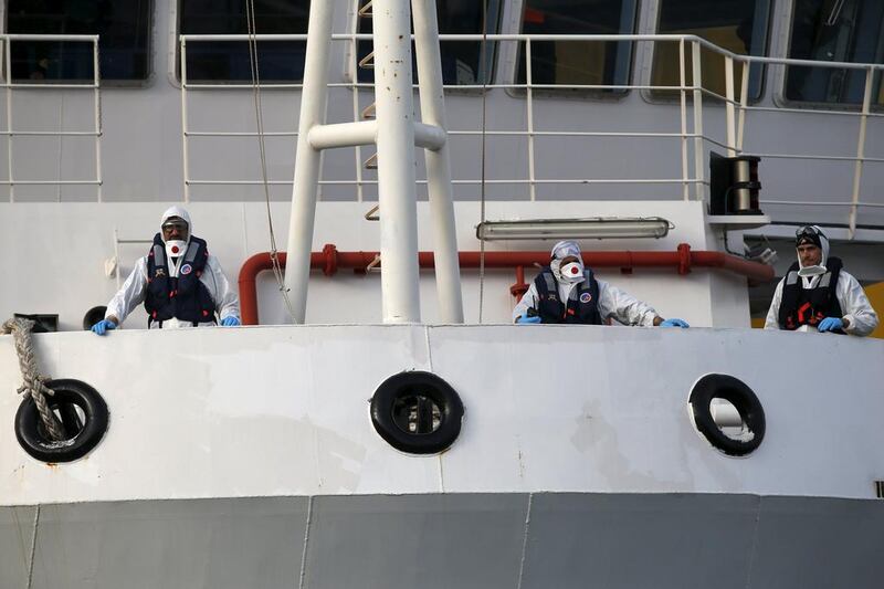 Italian coastguard personnel in protective clothing stand on the deck of their Bruno Gregoretti ship. Darrin Zammit Lupi / Reuters