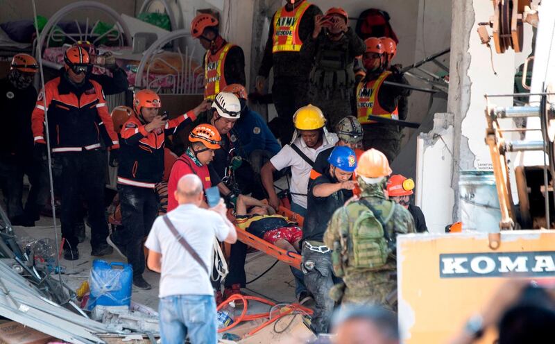 Rescue workers carry a survivor out of the collapsed Chuzon supermarket in Porac, Pampanga. AFP