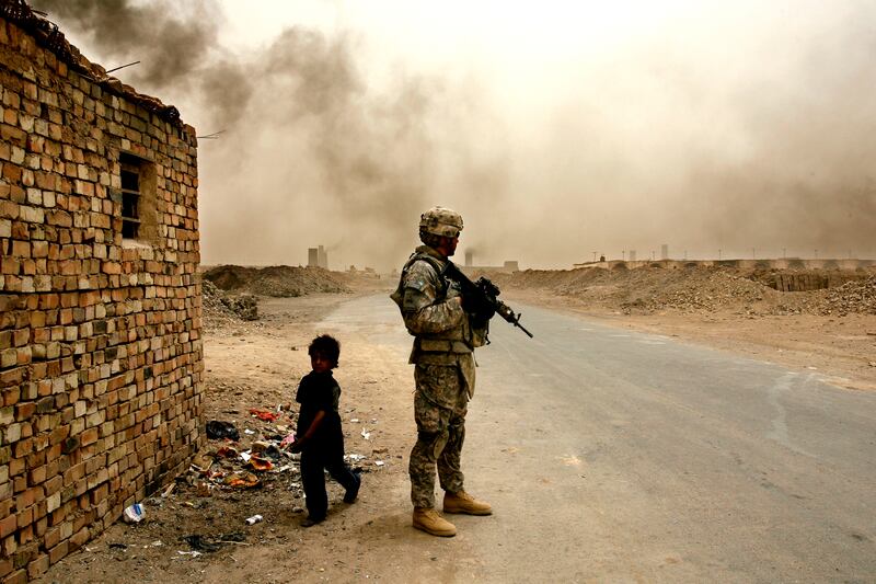 IRAQ, NARWAN - JULY 1: Iraqi child labourer, Salam (L) (6), walks past a US soldier with 4th Battalion/ 27th Field Artillery at a brick making factory on Tuesday, July 1, 2008 in Narwan, Iraq. (Photography by Warrick Page/The National)