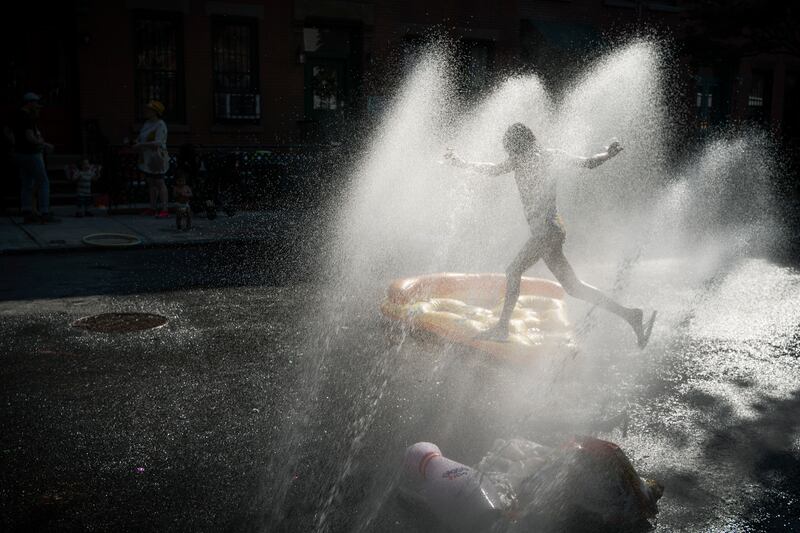 A child cools off in the spray of water from a fire hydrant during a block party in Brooklyn, New York. AP