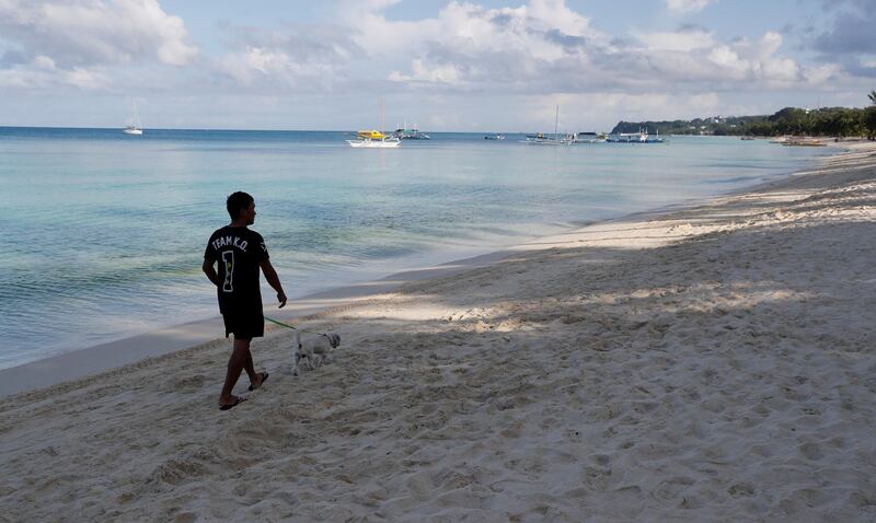 A resident walks his dog in an empty beach during the shutdown of the holiday island Boracay on April 26, 2018. Erik De Castro / Reuters