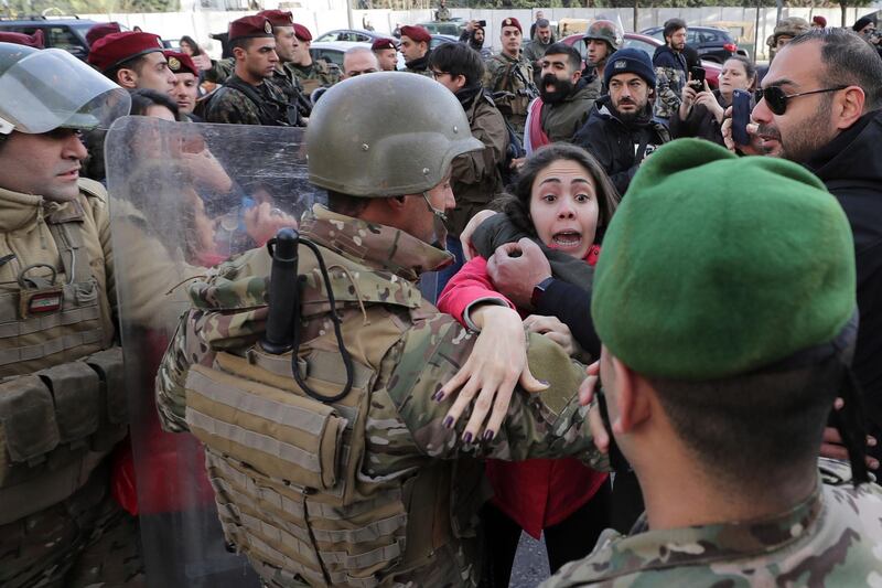 Anti-government protester scuffles with an army official after snatching her mobile phone during a demonstration outside the parliament building in downtown Beirut. AP