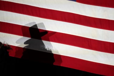 Tayler O'Dea, daughter of Joe O'Dea, Republican nominee for the U. S.  Senate seat held by Democrat Michael Bennet, casts a shadow on the American flag used as a backdrop at a primary election night watch party, late Tuesday, June 28, 2022, in Denver.  (AP Photo / David Zalubowski)