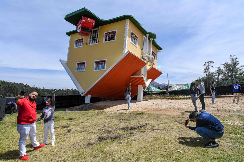 People pose for pictures outside the upside-down house designed by its Austrian owner Fritz Schall in Bogota, Colombia. AFP