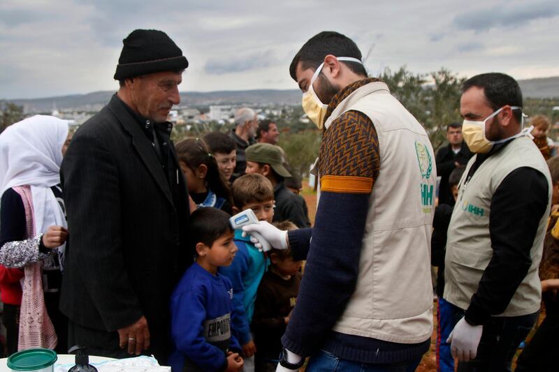 In this undated photo released by the Turkish humanitarian group IHH on Monday, April 6, 2020, aid workers of the group check the temperature of Syrian children at a camp for internally displaced persons in northern Syria. IHH via AP