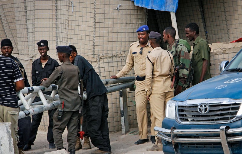 Somali police guard the road leading to the scene of a suicide bomb attack on a police academy in the capital Mogadishu, Somalia Thursday, Dec. 14, 2017. An Islamic extremist suicide bomber disguised as a police officer killed at least 10 people at a police academy in Somalia's capital on Thursday, police said.  (AP Photo/Farah Abdi Warsameh)