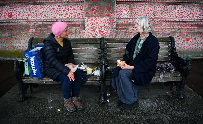 Women who lost their mothers to Covid-19 have lunch by the National Covid Memorial Wall in London. EPA
