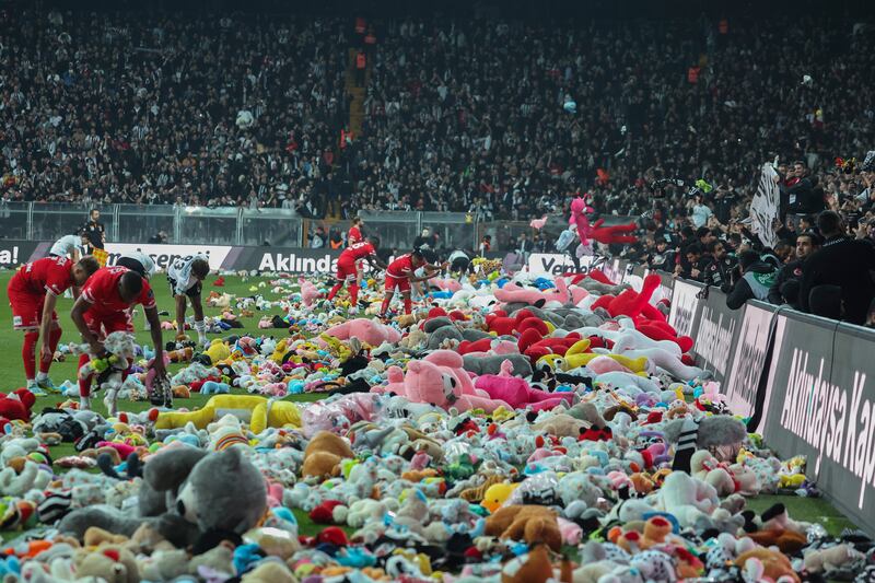 Players from Besiktas and Antalyaspor move toys to side of pitch after fans threw them down from stands. AP