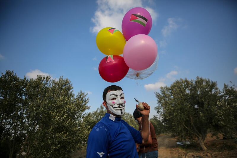 A protester holds balloons loaded with flammable material near the Gaza-Israel border.