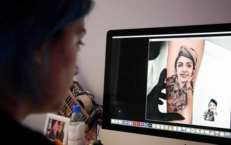Joa Antoun, a tattoo artist, works on a drawing of Sahar Fares, a firefighter who was a victim of last year's Beirut port blast.
