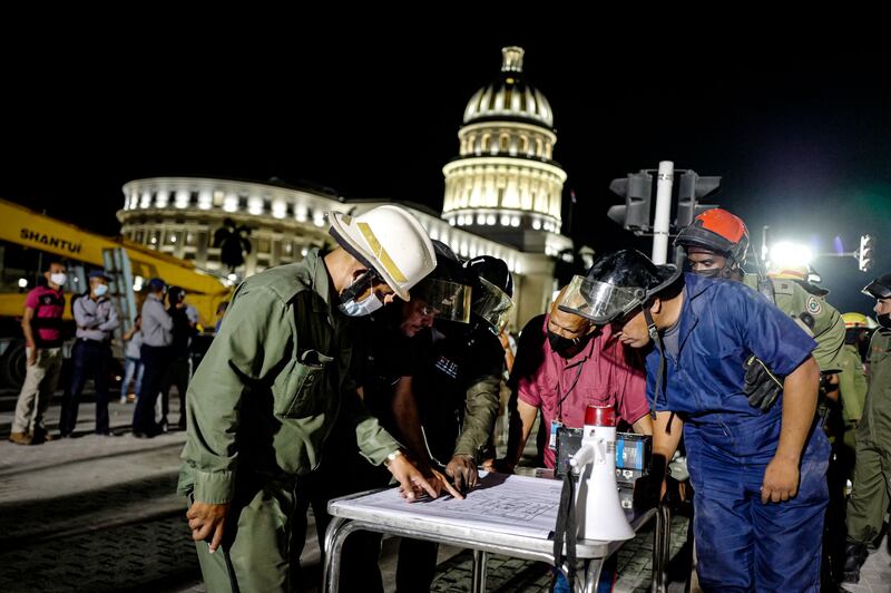 Firefighters look over a plan as rescue efforts continue after an explosion at the Saratoga Hotel in Havana, Cuba. AFP