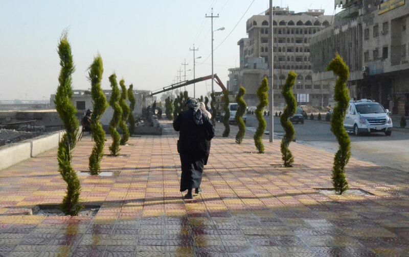 A woman walks in between newly planted trees in Iraq's Mosul. AFP