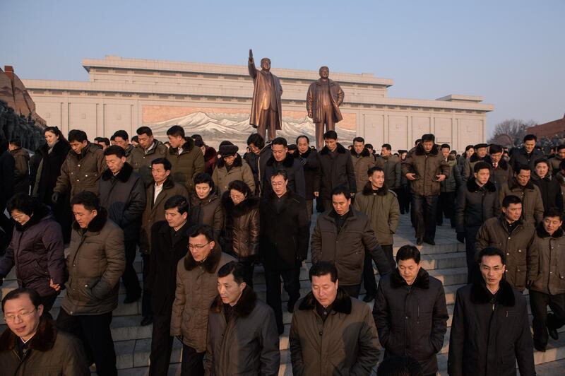 People leave after paying their respects before the statues of late North Korean leaders Kim Il Sung and Kim Jong Il. AFP