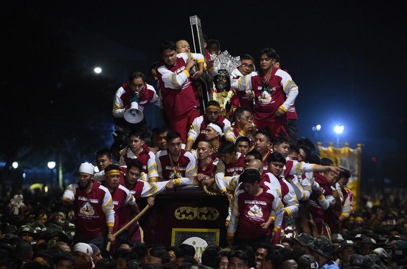 Guards or commonly called "hijos" (sons) ride atop a carriage transporting the statue of the Black Nazarene. AFP
