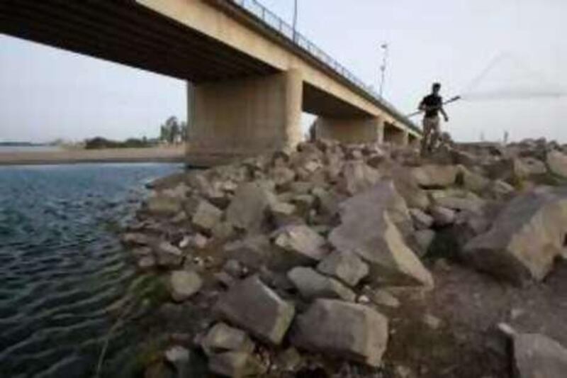 A fisherman walks down to the Euphrates River during the spawning season when fishing is illegal, near the new bridge in Raqqa City, Syria. Illegal hunting and fishing have hit the environment hard. 