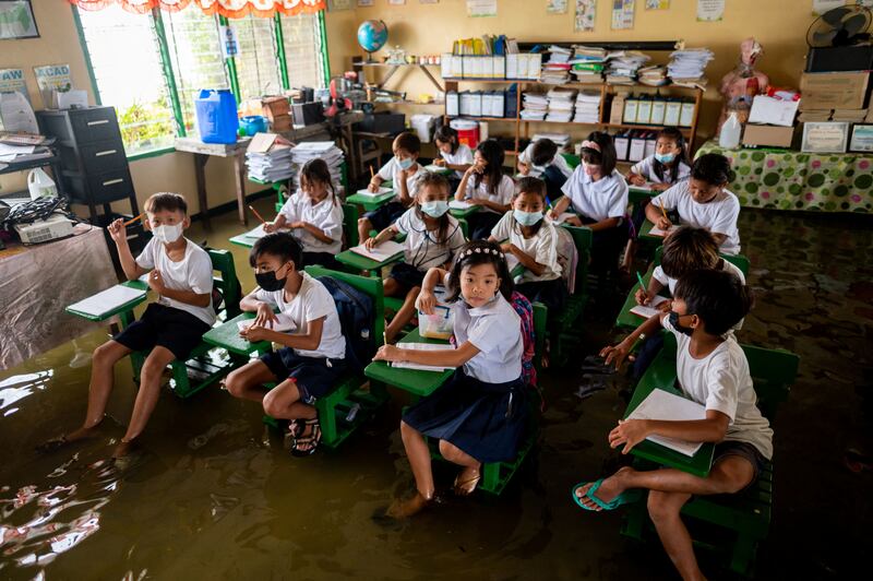 Pupils attend the first day of in-person classes at a flooded school due to high tide in Macabebe, Pampanga province. Reuters