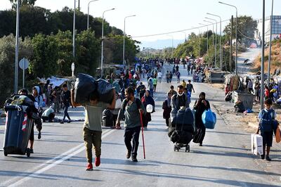 epa08675031 Asylum seekers from the destroyed camp of Moria walk to enter the new refugee camp at Kara Tepe on Lesbos island, Greece, 17 September 2020. A police operation takes place to convince asylum seekers to leave the road where they have camped since 09 September when a fire destroyed the camp of Moria, and to enter the new camp of Kara Tepe.  EPA/VANGELIS PAPANTONIS