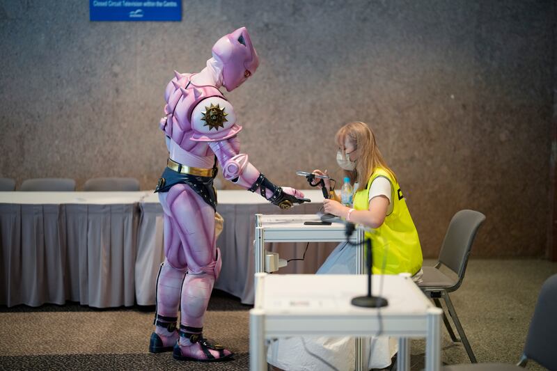 A costumed visitor receives his government contact tracing QR code in the LeaveHomeSafe coronavirus app scanned at Ani-Com and Games exhibition in Hong Kong on Friday. AP