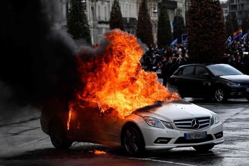 Flames rise from a car set on fire during a demonstration in Rennes, north-western France. AFP