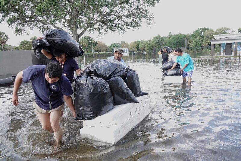 People wade with their belongings through high floodwaters in Fort Lauderdale, Florida. AP