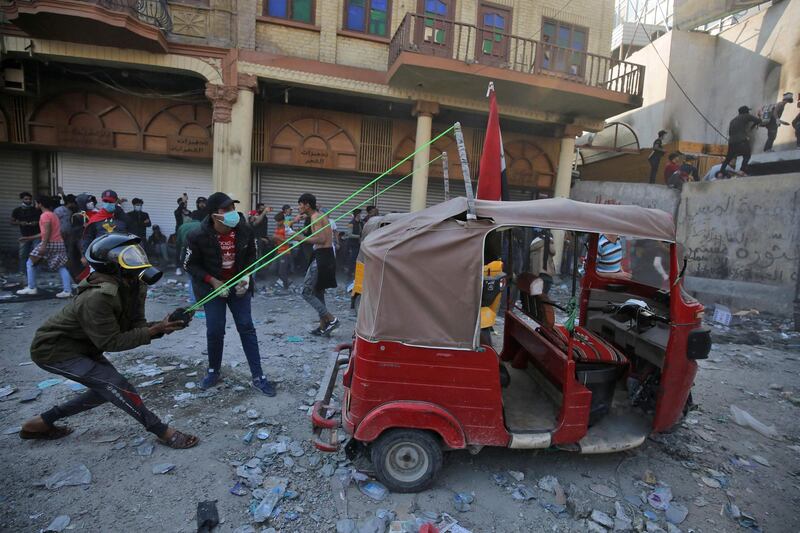 An Iraqi demonstrator uses a slingshot affixed to a tuk tuk car amid clashes with security forces in the capital Baghdad's al-Rasheed street near al-Ahrar bridge during ongoing anti-government demonstrations.  AFP