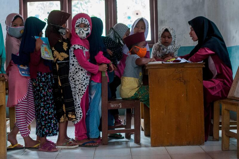 Children wearing protective face masks queue during teaching and learning activities amid the coronavirus outbreak in Lebak, Banten Province, Indonesia. Reuters