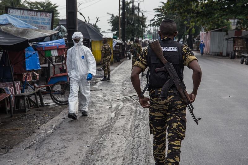 A member of the Covid-19 operational centre (CCO) is seen as soldiers form the Malagasy Gendarmerie patrol the streets of Toamasina, a port city in eastern Madagascar, where containment measures have been reinforced since June 1.   AFP