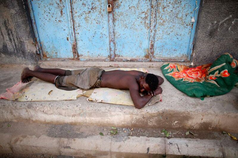 A man from the Akhdam community sleeps on the side of a street.