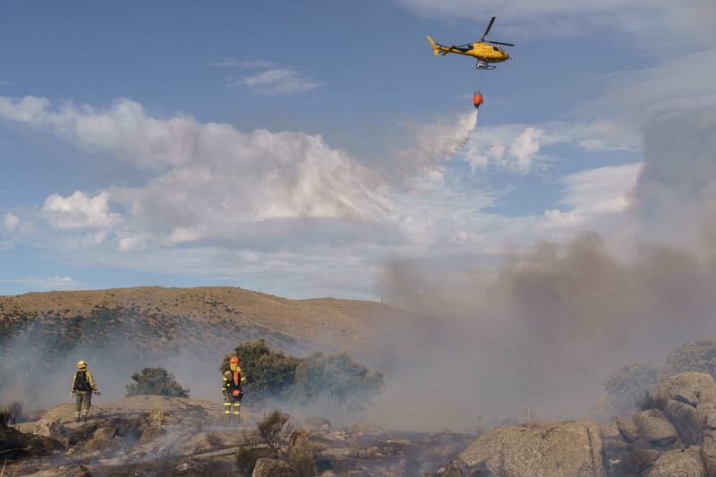 A helicopter drops water as fires blaze between Navalcruz and Riofrio near Avila, central Spain, on August 15. AFP