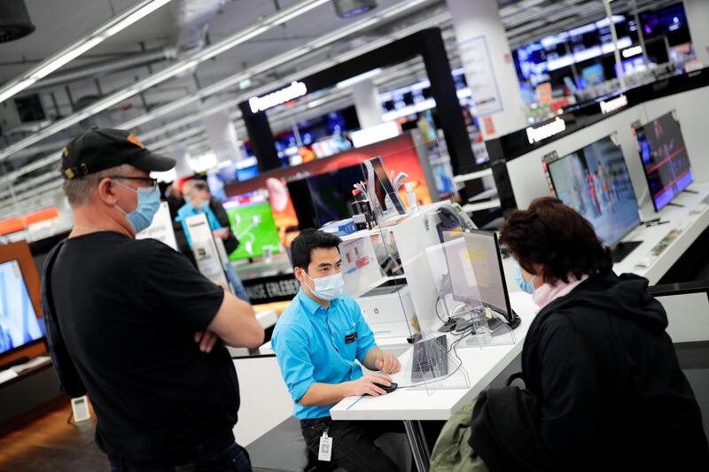 An employee helps customers at a Saturn electronic store as the coronavirus lockdown measures are eased in Berlin, Germany. Reuters