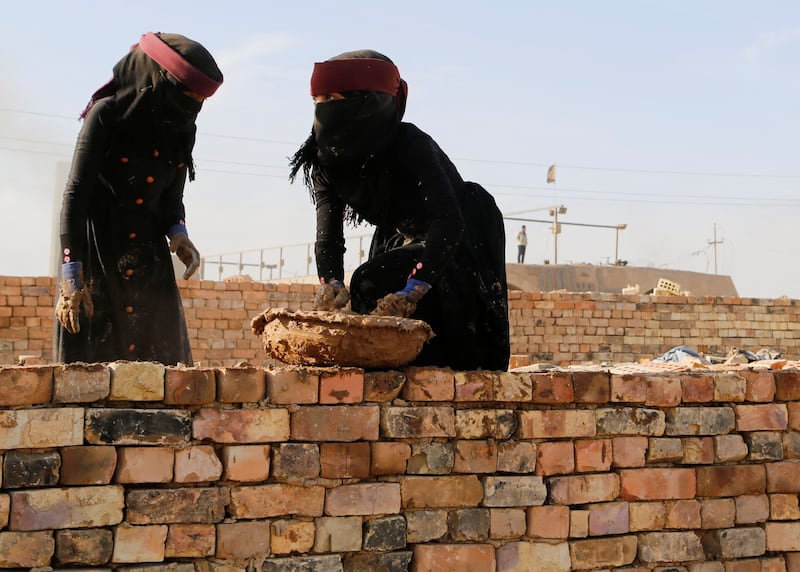Labourers, their faces covered against dust, at work at the brick factory.  Reuters