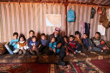 Abderrazaq Khatoun, rests with his 11 orphaned grandchildren, inside a tent in an encampment in the village of Harbanoush, in the northern countryside of Syria's northwestern province of Idlib, on March 11, 2021. The Syrian war robbed Khatoun of 13 of his children and one of his wives, but he was forced to overcome his grief quickly to raise 11 orphaned grandchildren. Displaced from his native home in central Hama province, the 83-year-old retired farmer and 30 surviving family members have pitched four tents on a strip of land surrounded by olive trees. / AFP / Ahmad al-ATRASH