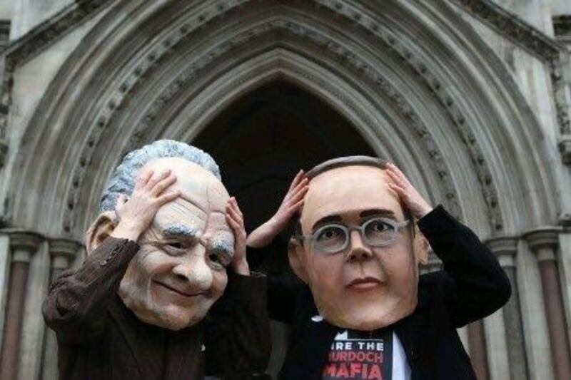 Protesters from a campaign group demonstrate outside the High Court where the Levenson Inquiry is taking place wearing oversized masks of James, right, and Rupert Murdoch.