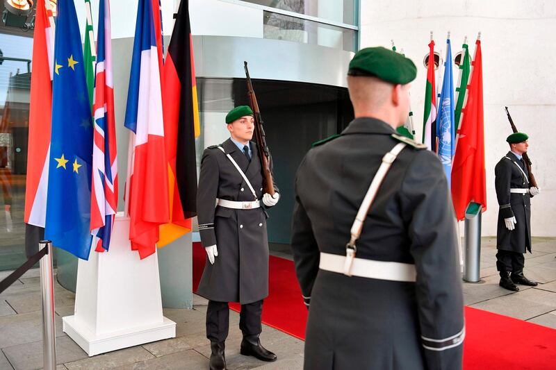 Guards stand next to the flags of the participating countries at the entrance of the German Chancellery in Berlin before the arrival of the participants in the peace summit on Libya.  AFP