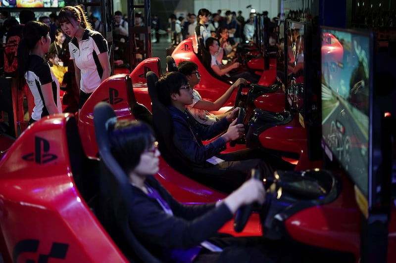 Visitors try out a car driving game at the Tokyo Game Show in Chiba, near Tokyo Thursday, Sept. 21, 2017. The Japanese video game industry is back, after suffering years of the doldrums, with decades-old titles being adapted for revamped technology. That energy was amply evident at the Tokyo Game Show, an annual event showcasing video games. (AP Photo/Eugene Hoshiko)