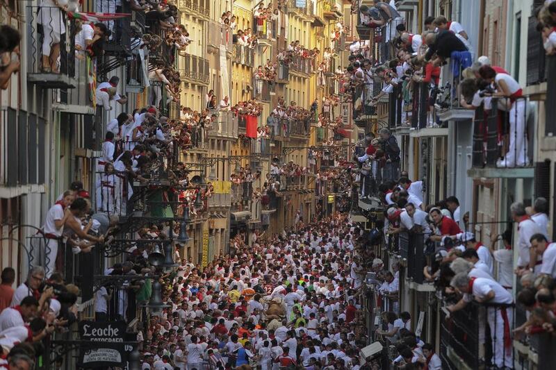 People watch participants from balconies as they run in front of Alcurrucen's bulls during the first bull run of the San Fermin Festival, on July 7 in Pamplona, northern Spain. Pedro Armestre / AFP

