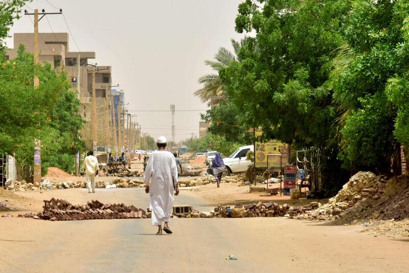 Sudanese residents walk by barricades in Khartoum on June 9, 2019. Sudanese police fired tear gas on June 9 at protesters taking part in the first day of a civil disobedience campaign, called in the wake of a deadly crackdown on demonstrators. Protesters gathered tyres, tree trunks and rocks to build new roadblocks in Khartoum's northern Bahari district, a witness told AFP, but riot police swiftly moved in and fired tear gas at them. / AFP / Ahmed Mustafa                       
