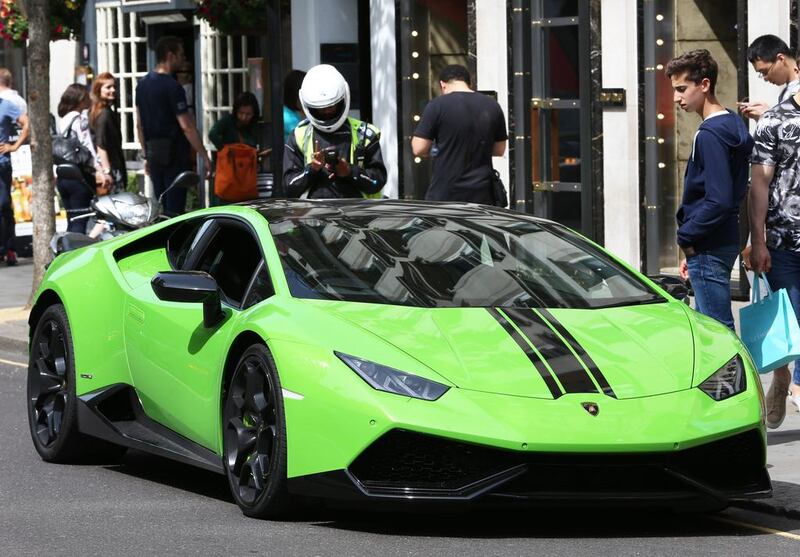 A Lamborghini super car parked illegally in Knightsbridge, London, as a parking attendant starts to issue a ticket. (Stephen Lock for the National)