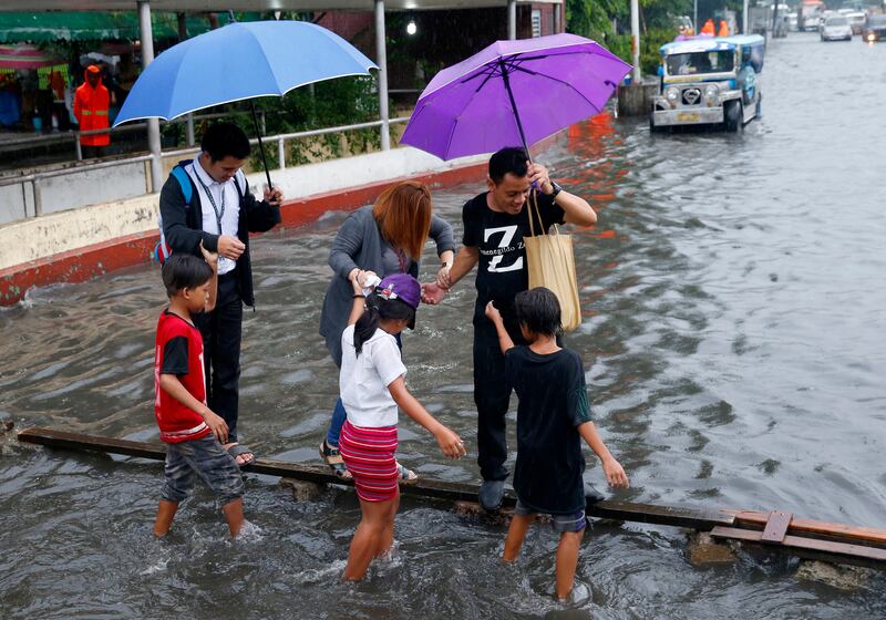 Commuters cross on a wooden plank for a fee to avoid a flooded street after heavy rains brought about by tropical storm 'Nesat' flooded some parts of metropolitan Manila. Bullit Marquez / AP Photo