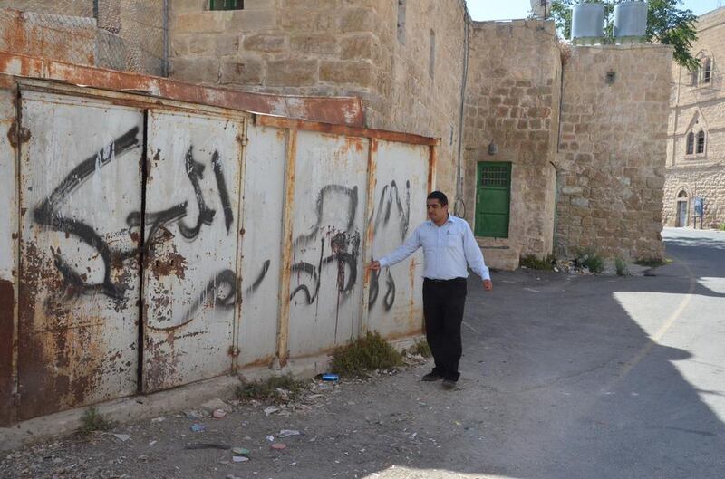 Badee Dwaik, of the non-government organisation Human Rights Defenders, points out grafitti on a wall in occupied Hebron, H2, that says "death to Arabs". Kate Shuttleworth for The National