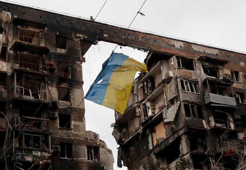 A torn Ukrainian flag hangs in front a damaged apartment building in Mariupol. Reuters