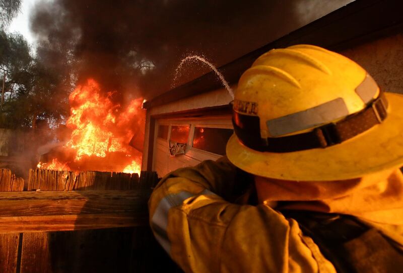 A Los Angeles County firefighter puts water a burning house in a wildfire in the Lake View Terrace area of Los Angeles. Chris Carlson / AP Photo