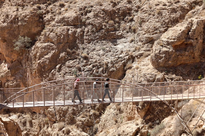 People walk on a bridge at Deir Mar Moussa Al Habashi.