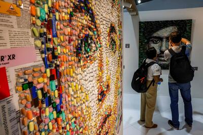 A Cop27 delegate takes photos of a portrait by Turkish artist Deniz Sagdic. AFP 