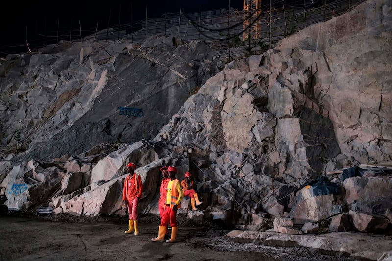 Construction workers stand next to a big rock wall  at the Grand Ethiopian Renaissance Dam (GERD), near Guba in Ethiopia.  AFP